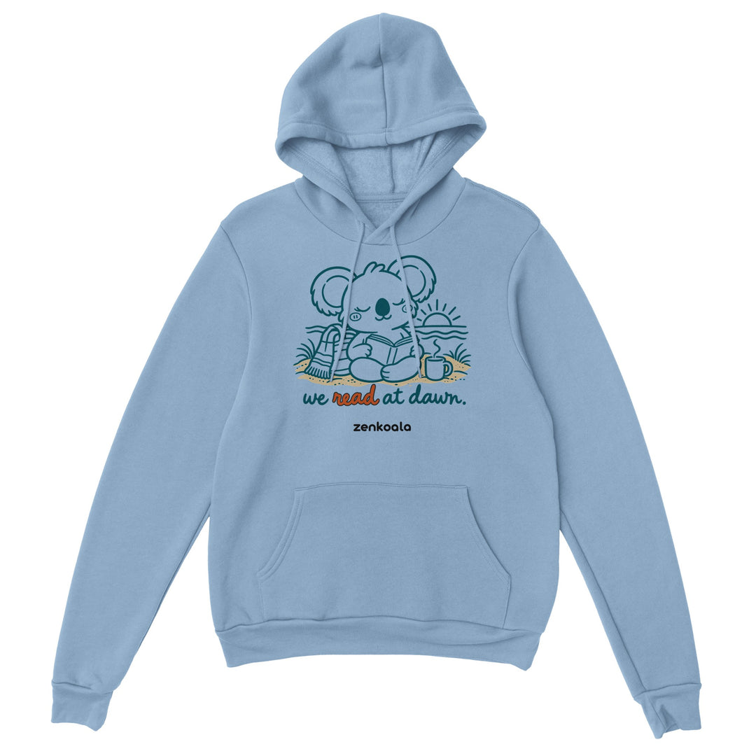 We Read at Dawn feel-good hoodie in light blue: a koala reading on the beach, Zen Koala Australia