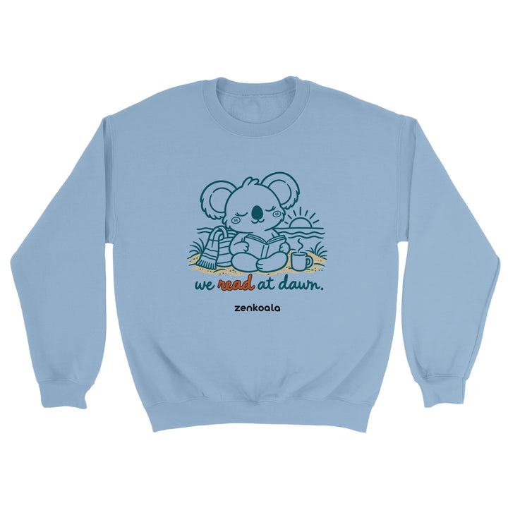 We Read at Dawn feel-good sweatshirt in light blue: a koala reading on the beach, Zen Koala Australia