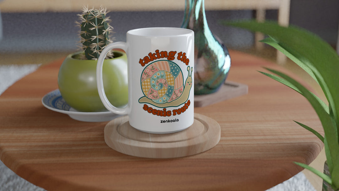 Taking the Scenic Route Snail 15oz mug on a wooden table with a cactus, Zen Koala Australia