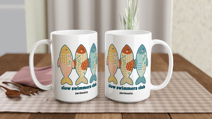 Two Slow Swimmers Club 15oz mugs on a table, showing both sides of the design, Zen Koala Australia